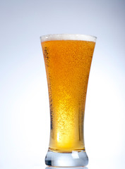 Glass of beer with froth close up on white