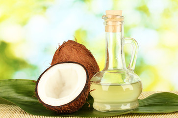 decanter with coconut oil and coconuts on green background