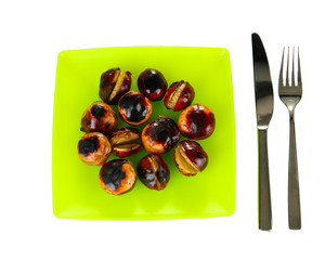 roasted chestnuts in the green plate with fork and knife