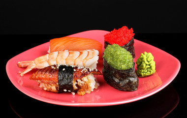 delicious sushi served on red plate isolated on black