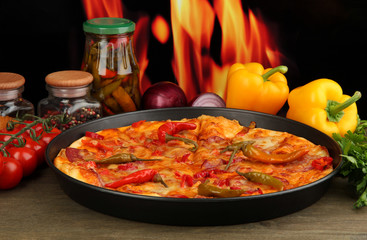 Tasty pepperoni pizza in pan with vegetables on flame