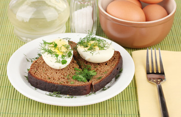 Boiled eggs  on dark bread on green background