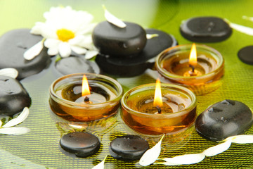 spa stones with flowers and candles in water on plate