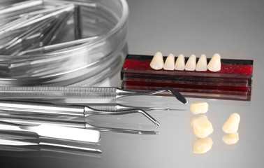 Set of dental tools with denture on grey background
