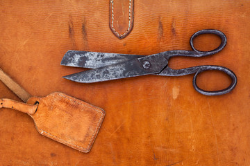 Scissors on vintage leather background with label