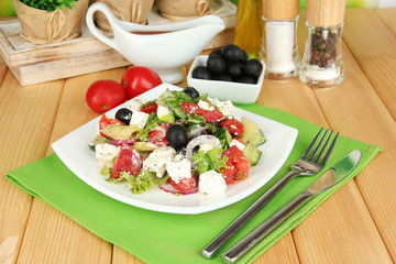 Fresh greek salad on plate on wooden table close-up