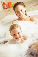 Mother And Daughter Relaxing In Bubble Filled Bath