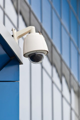 Surveillance camera on a background of blue glass wall