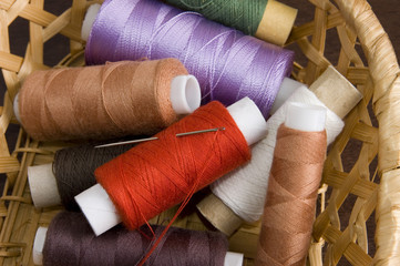 Multicolored thread spools in woven basket close-up
