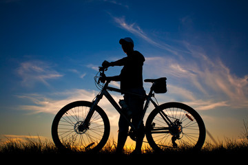 Obraz premium cyclist with a bike silhouette on a blue sky