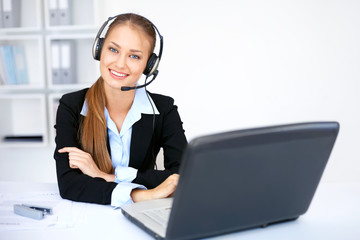 Portrait of pretty young female operator sitting at office desk