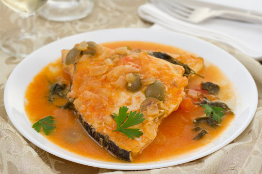 fish with tomato sauce on the white plate