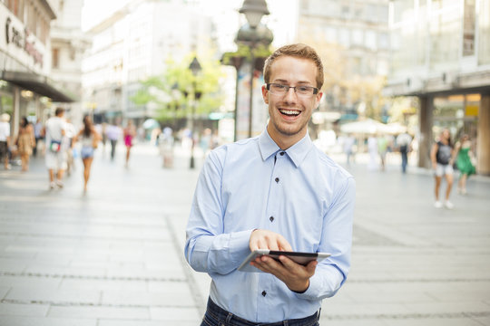Smiling Businessman with tablet on urban street