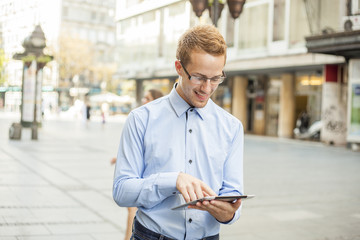 Smiling Businessman with tablet on street