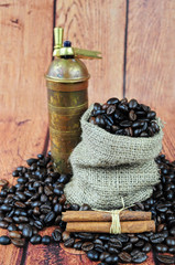 Coffee beans in burlap sack, vintage grinder and cinnamon sticks