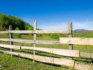 An old wood fence with a green country field behind it