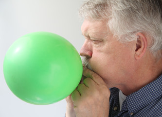 senior man blowing up balloon