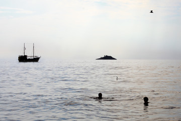 boat at sea with people swimming
