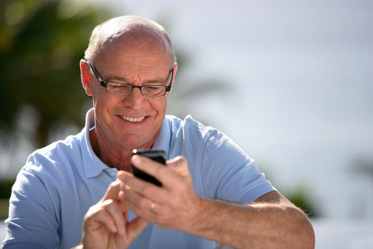 Cheerful senior sending text message