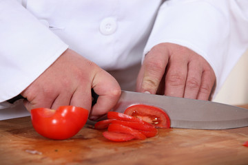 A cook slicing a tomato