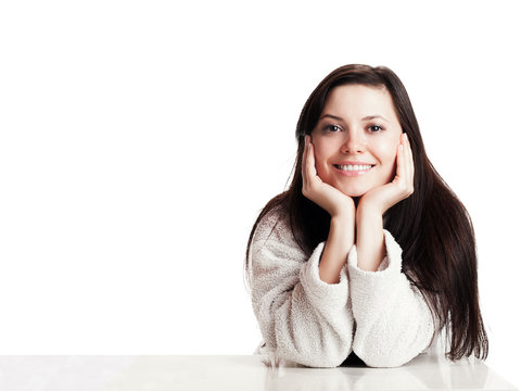 Young woman propped up on a table and smiles - isolated