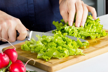 Young woman making salad in kitchen