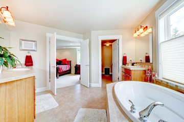 Large bathroom with white tub and open door to bedroom.