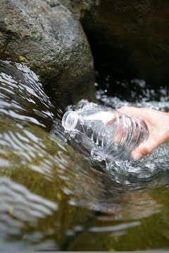 Filling Up Bottle Of Water By A Stream