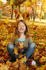Girl playing with autumn leaves outdoors