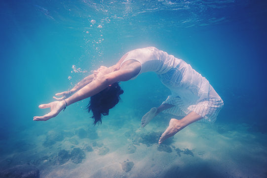 Underwater woman portrait with white dress into the sea.