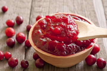 Cranberries jam closeup in bowl on wooden boards