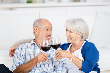 älteres paar stößt mit rotwein an