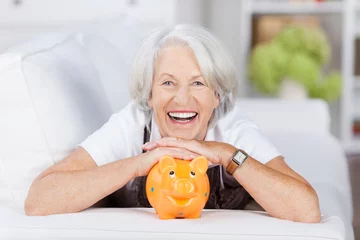 Fotobehang lachende seniorin mit ihrem sparschwein © contrastwerkstatt