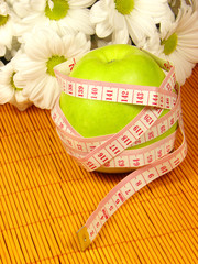Green apple, flowers and measuring tape