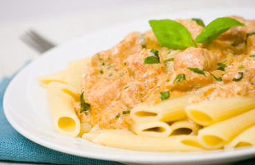 Penne pasta with chicken meat, cream sauce and basil