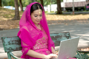 Pretty woman in Pink Indian clothes with laptop .