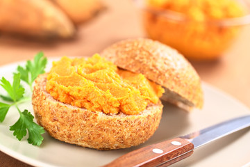 Sweet potato spread on wholegrain bun on plate with knife