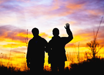 Two men stand in the background of a sunset © Oleg Fedorov