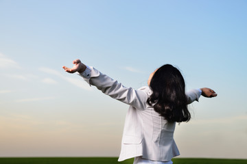 A woman in a business suit with their hands raised