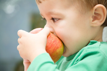 Little child is biting red apple and smile