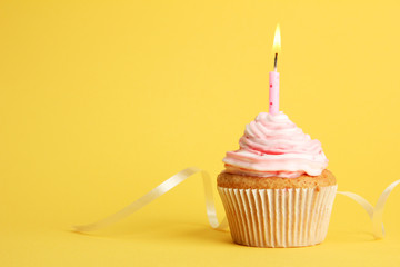 tasty birthday cupcake with candle, on yellow background