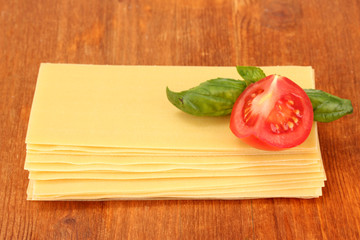Uncooked lasagna pasta on wooden background
