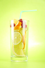 transparent glass with citrus fruits, on green background