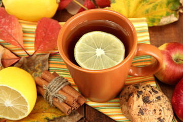 cup of hot tea and autumn leaves, on wooden table