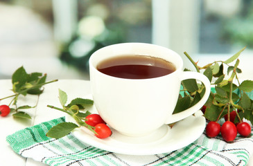 cup of tea with hip roses, on wooden table