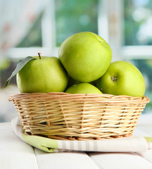 Ripe green apples with leaves in basket,