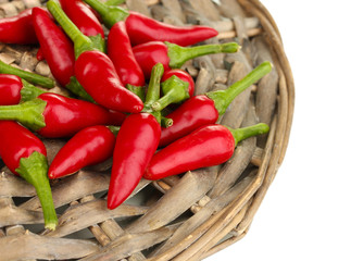 little hot peppers on wicker mat isolated on white
