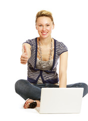 A young girl with a laptop sitting on the floor, showing ok