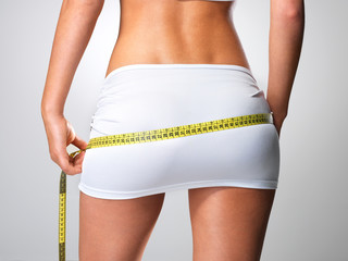 Sporty woman with slim body measuring hips