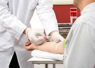 A doctor with syringe is taking blood for test